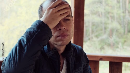 A middle-aged man touches his head with a pained expression, showing signs of a severe headache. Perfect 4K video for health, stress, and medical-related content.