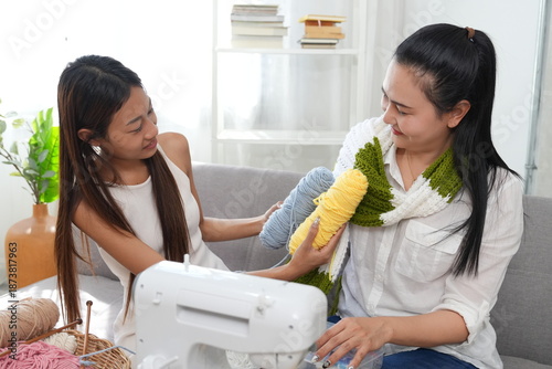 Mother and daughter sew and knit together, teaching the daughter to sew in the living room