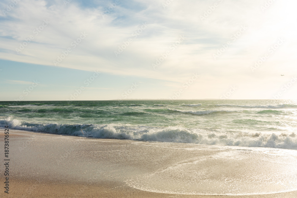Fototapeta premium Sea waves splashing on shore at beach against sky with clouds at sunny day