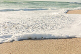 White sea foam with wave splashing on shore at beach on sunny day