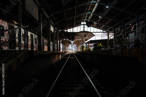 Dark or silhouette station with straight train rails into the light at Tugu Station Yogyakarta.