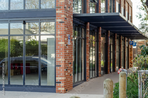 An empty corner retail unit with glass frontage at street level along a pedestrian walkway. Unoccupied commercial shop space suitable for retail or service use at an urban corner location.
