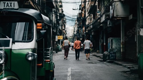 Wallpaper Mural Three individuals walking down a narrow urban street with a distinctive tuk-tuk vehicle in the foreground, evoking a sense of travel and local culture Torontodigital.ca
