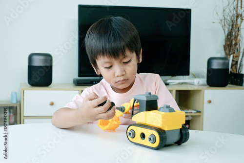 Cute boy kid fixing his broken excavator toy