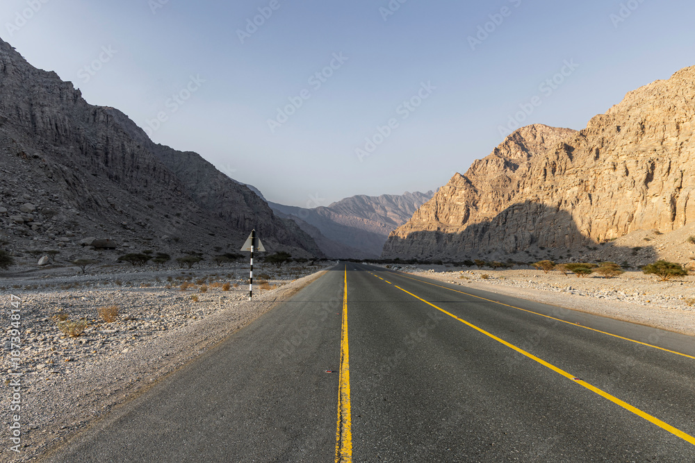 Naklejka premium Mountain road background with a stunning view of Jebel Jais under a cloudy sky, a beautiful travel destination in Ras Al Khaimah.