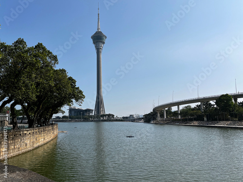 Scenic, sunlit view of the Macau Tower towering over the Sai Van Lake in Macau