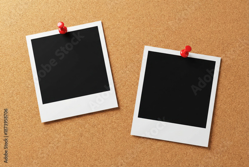 Two blank instant photo prints pinned to a corkboard with red pushpins