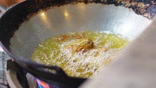 Chicken being fried in hot oil, showing cooking process of crispy fried chicken with sizzling oil.