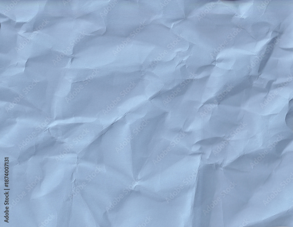 Fototapeta premium Crumpled blue paper texture on a flat surface in bright light during the day