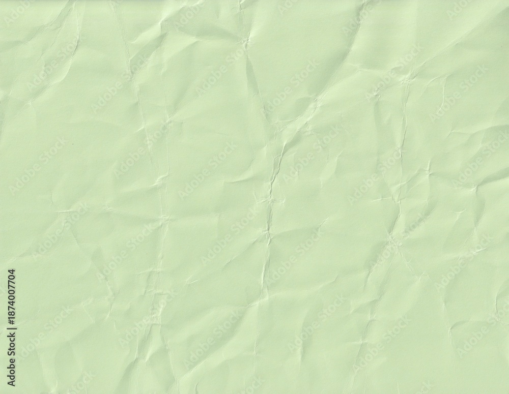 Obraz premium Textured paper surface with wrinkles and creases displaying a light green color and soft shadows in a simple layout