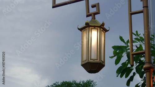Traditional Chinese-style lantern post in gold with intricate designs stand tall under the afternoon sky