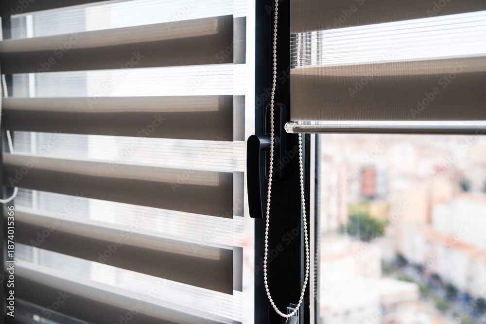 Naklejka premium Close-up of zebra roller blinds fabric texture on window with adjustable light control in modern home