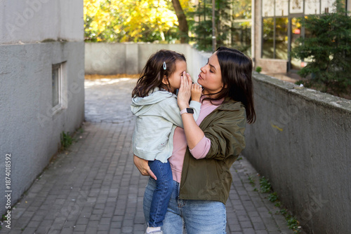 Photos Mother checking little daughter eye outdoors, caring parent examining child heal