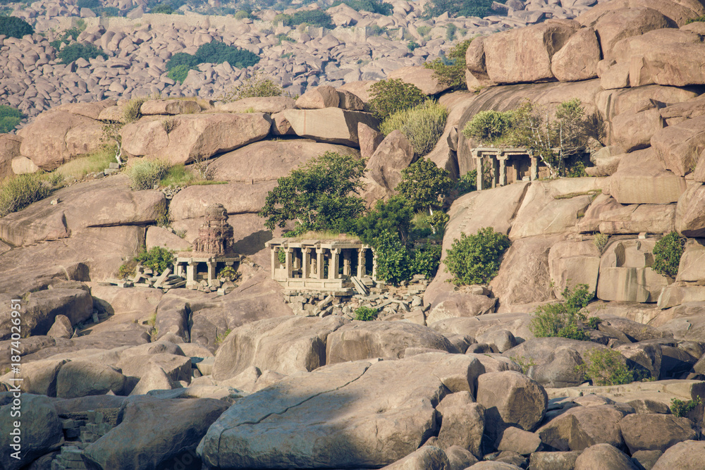 Fototapeta premium Ancient temples nestled among large rocks in a hilly area during daylight