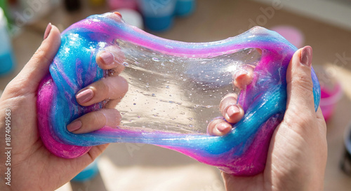 Close up of hands stretching translucent blue and pink glitter slime representing sensory play and stress relief, visual asmr