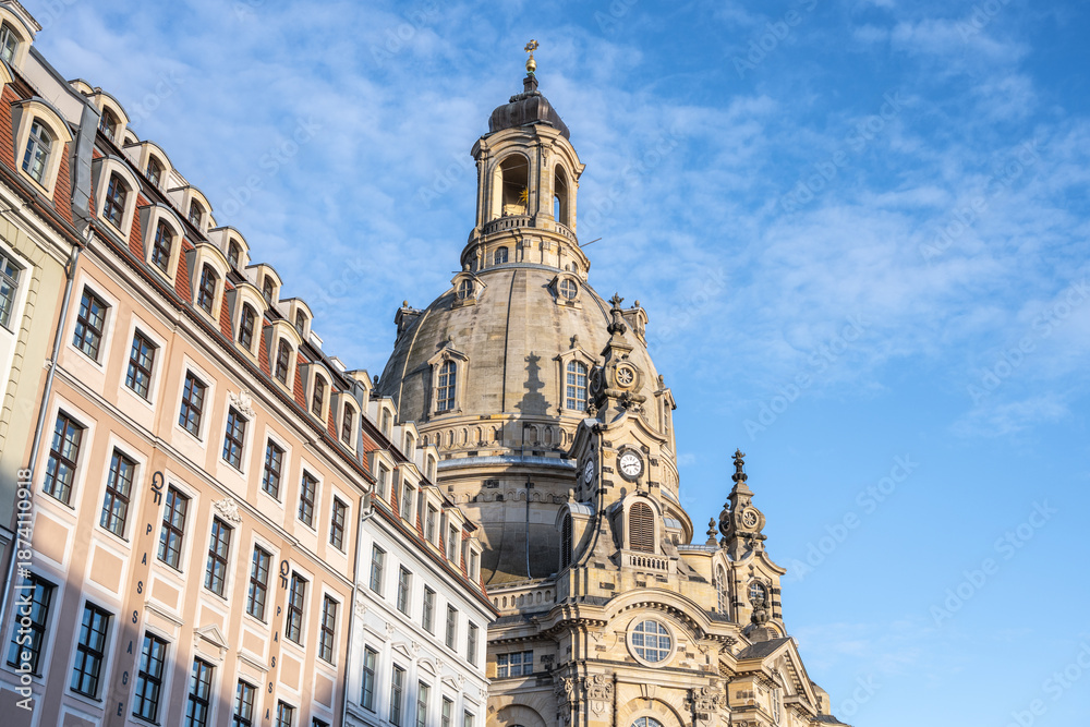Obraz premium Frauenkirche in Dresden showcases its large dome against a blue sky. The church is surrounded by historic buildings, creating an interesting view. Many visitors enjoy the scenery.