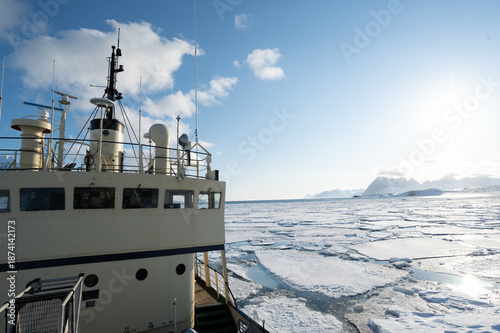 A research vessel navigates through icy waters, likely on an expedition to study Arctic or Antarctic environments. The ship's equipment suggests scientific research or exploration.