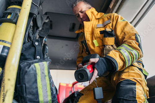 Φωτογραφία Firefighter preparing thermal imaging camera in firetruck