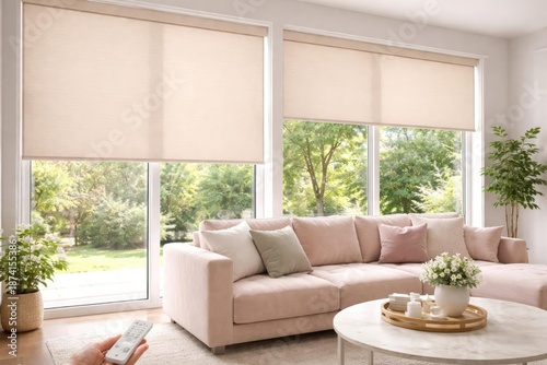 Beige motorized roller shades by remote alongside a pastel velour sofa and visible summer trees
