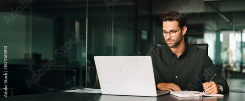 Foto Young adult European man looking at laptop pc screen