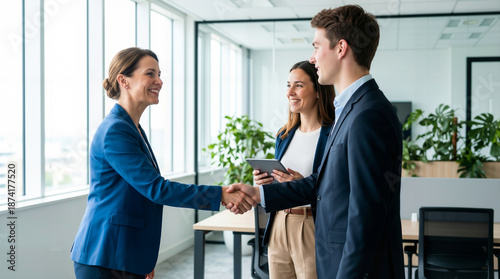 Successful business colleagues shaking hands and smiling in a modern office, celebrating a partnership or deal