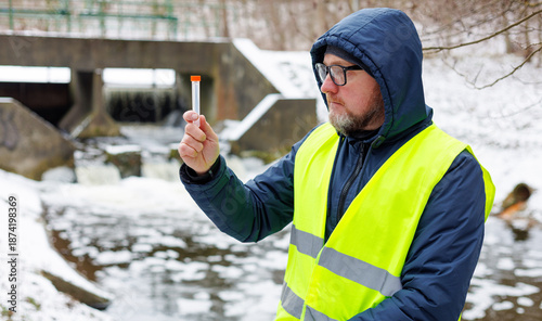 Bilde på lerret Male ecologist collected a meltwater sample for analysis near a sluice gate in a snow covered forest during winter
