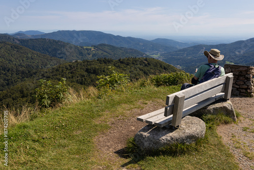 randonneur assis sur un banc au sommet du Ballon d'Alsace dans les Vosges en train d'admirer les paysages de forêts vosgiennes