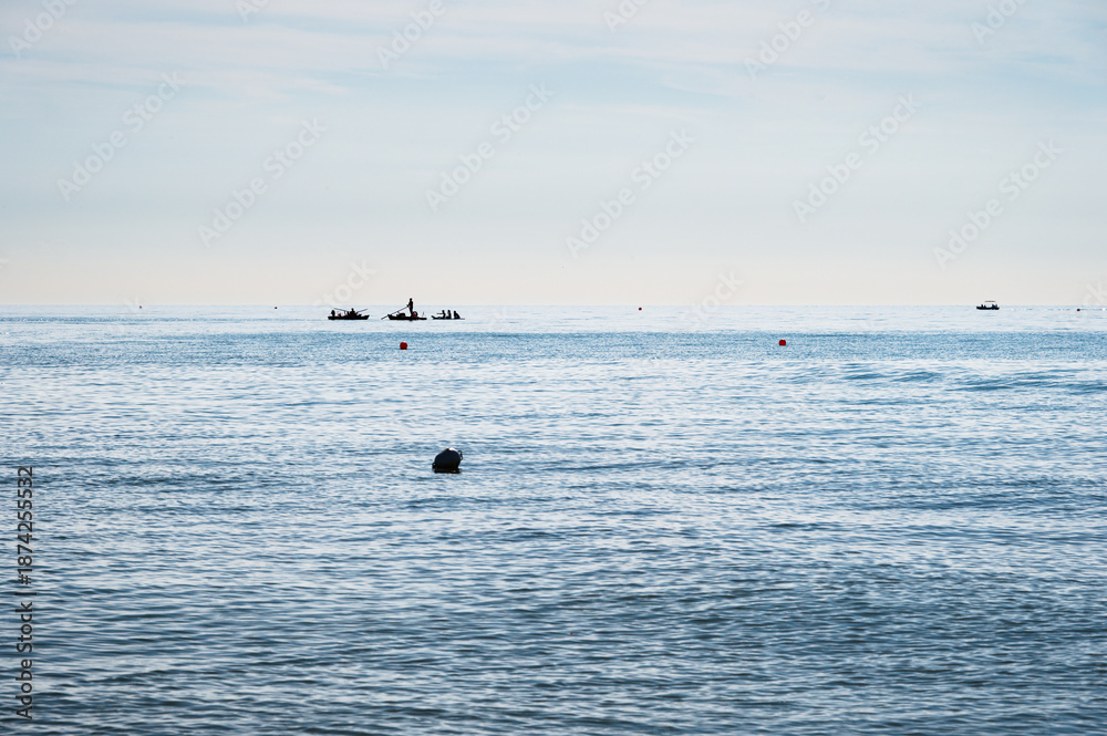 Obraz premium people silhouette on a boat in front of a Adriatic Sea beach during a summer day, Bibione Pineda, Venice, Italy