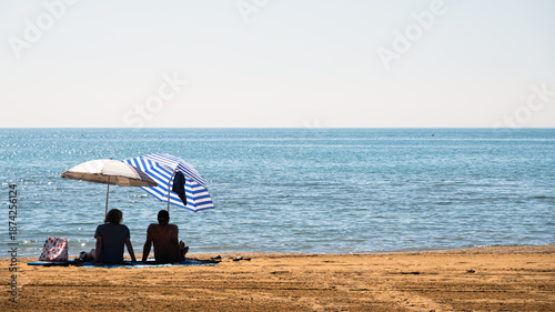 people silhouette on a boat in front of a Adriatic Sea beach during a summer day, Bibione Pineda, Venice, Italy