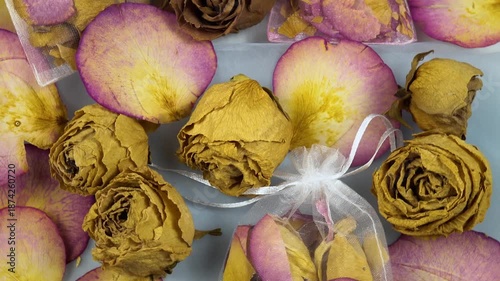 Organza sachets filled with dry rose petals, dried rose buds lie on a table, top view