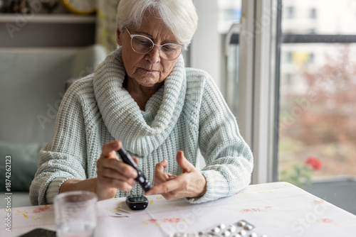 Senior Woman Checking Her Blood Sugar Levels by Glucose Meter at Home
