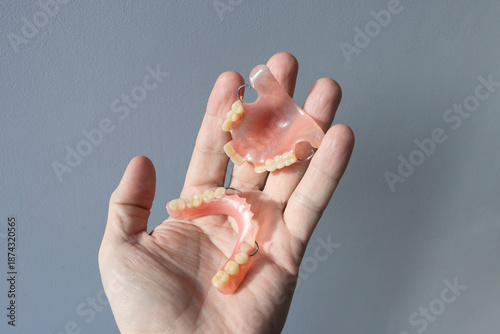 A person holds plastic, nylon, removable dentures in his hand.