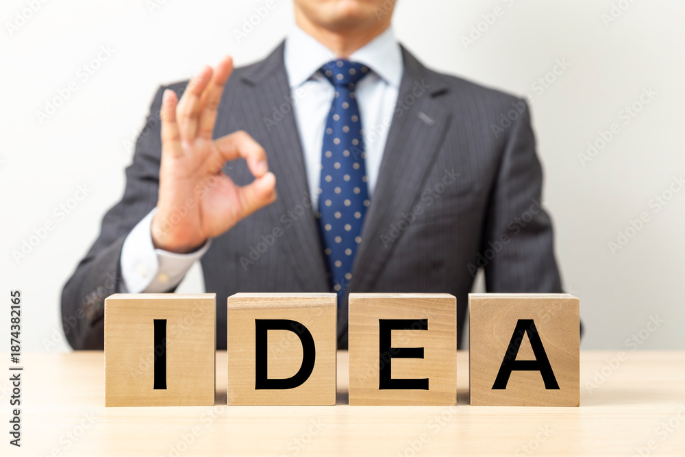 Obraz premium 「IDEA」と書かれたブロックとOKポーズをするビジネスマン