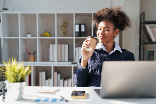 Tableau sur toile African American woman having a coffee break during work, smiling with closed ey