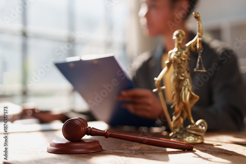 Konstfotografi Lady Justice statue and a wooden gavel on a table, with a lawyer reviewing docum