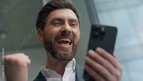 Schilderij op canvas Close up happy smiling Caucasian middle-aged business man winning with mobile ph