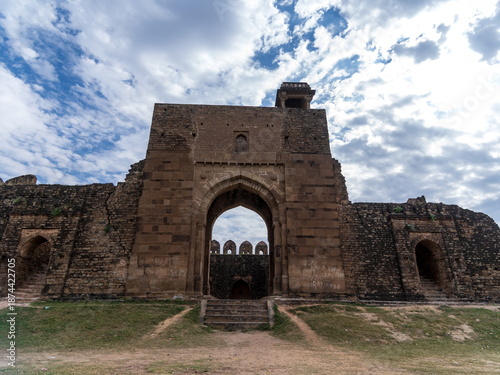 View of the weathered Rohtas Fort's grand gate stands against a striated sky, its stone walls whispering tales of history, Rohtas Fort, Punjab, Pakistan.