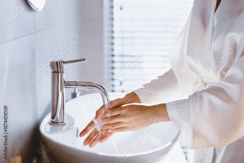 Fotografija A person is washing their hands at a modern sink in a bathroom