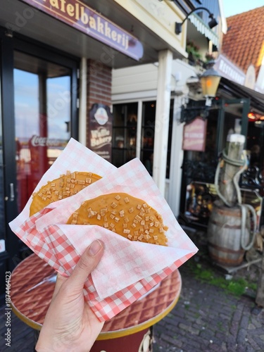 Classic Stroopwafel in hand. Traditional sweet food stroopwafels with caramel in Holland. Dutch two Cookies bakery