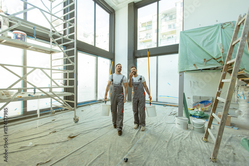 Tableau sur toile Workers carry paint buckets in a new building during renovation process