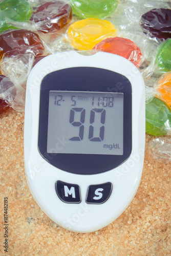 Glucose meter with sugar level, candies and cookies. Healthy nutrition and reduction eating sweets during diabetes