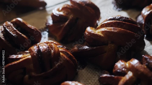 Freshly baked, fragrant Scandinavian buns with cinnamon and cardamom cool on a baking sheet in the morning sun. Cozy hygge  bakery concept. Morning buns.