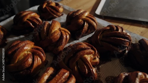 Freshly baked, fragrant Scandinavian buns with cinnamon and cardamom cool on a baking sheet in the morning sun. Cozy hygge  bakery concept. Morning buns.