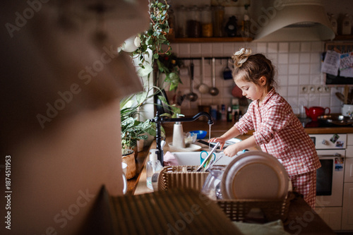 Billede på lærred Independent child doing dishes at home.