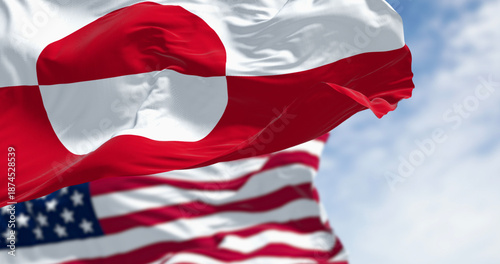 Flags of Greenland and the US waving in the wind on a clear day © rarrarorro