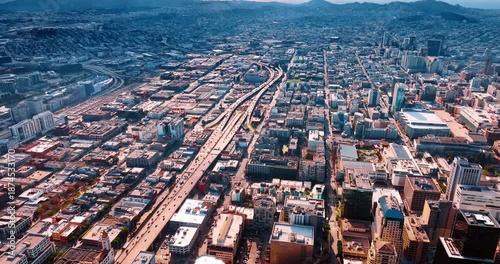 Hectic traffic on the modern intertwining highways through the dense cityscape. Footage high above the vast urban landscape of San Francisco, California, United States on sunny day.