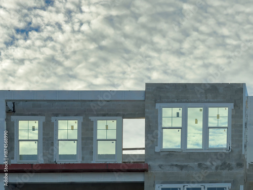 Row of new windows, with stickers, on the top floor of a large multistory senior living facility under construction on a cloudy afternoon in southwest Florida