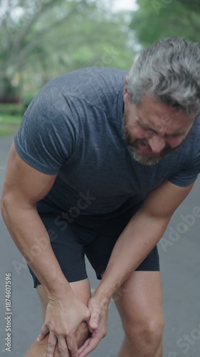Knee joint dislocation after running. Sport injury. Arthritis. Man massage knee at pain point. Running injury outdoor. Knee pain during workout. Painful trauma. Man runner has knee pain. 4k vertical
