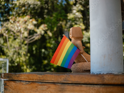 Hand holding rainbow flag on balcony, pride and social inclusion concept