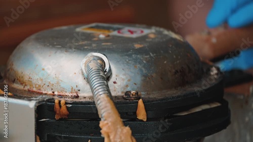 A close-up of the batter being poured onto a hot waffle iron. The mixture spreads evenly into the indentations, creating a delicious treat. The waffle iron is closed and flipped